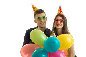 young guy with a girl, holding near the eye paper glasses happily laughing and carrying balloons photo