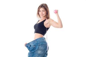 Slim young girl standing in the wide trousers and shows muscle on hand isolated  white background photo