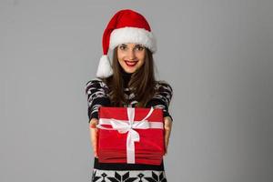 woman in warm sweater and santa hat with red gift photo