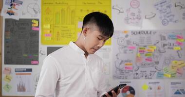 Portrait of attractive businessman texting message on smartphone at workplace. Smiling man using cellphone at office room. Cheerful man drinking hot coffee. video