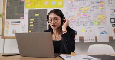 vue latérale de lunettes de femmes heureuses porte un casque d'appel vidéo sur un ordinateur portable. conférencier webinaire de femme d'affaires diffusant une formation Web en direct. agent du centre d'appels, responsable du support technique parlant au client. video