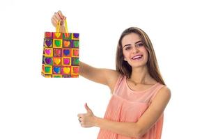 beautiful smiling girl raised in hand a bright colorful package isolated on white background photo