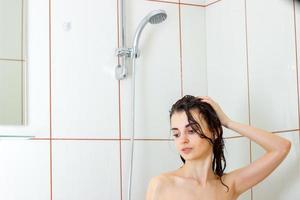 hermosa joven con el pelo mojado para limpiar la ducha foto