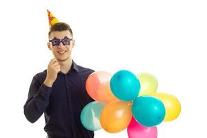 un joven alegre se mantiene cerca de gafas de papel y muchas bolas de colores foto