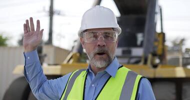 porträtt caucasian chef bär hjälm och säkerhet väst med glasögon presenter och rekommenderad arbetsplats medan arbetssätt i frakt hamn, logistik transport begrepp. video