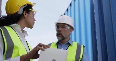 hübsche ingenieurin, die an einem laptop arbeitet, ein kaukasischer betriebsleiter mittleren alters, der hereinkommt und die verzögerung beim laden von containern im versandhafen, logistiktransportkonzept, beschuldigt. video