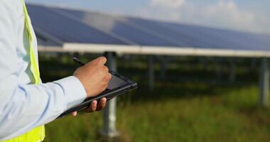 Hand of young engineer man use digital pen write on tablet while checking operation in solar farm video