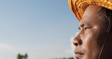 Close up portrait of a young farmer man eyes looking at evening sunset sunlight or golden light wearing a straw hat macro slow motion video