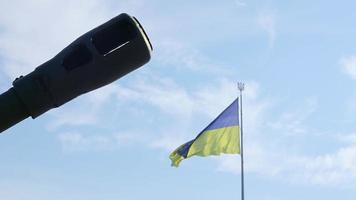 Groups of ancient military guns against the background of the State Flag of Ukraine. Muzzle brake of an artillery gun. Sunny morning sky. Call to stop violence concept. Ukrainian flag. video