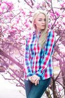 Verical portrait of modest young blonde girl with pink flowers photo