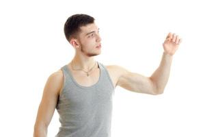 un joven con la camisa gris mira hacia levanta la mano y estira los músculos foto