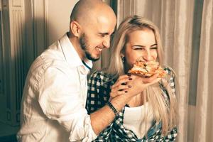 alegre pareja enamorada divirtiéndose con pizza en la fiesta foto