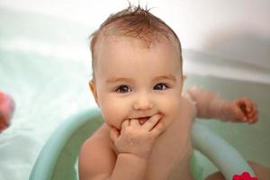 Cute newborn girl bathes in the bathroom photo