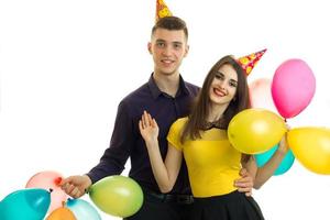 joven gay con una chica con conos en la cabeza llevando globos y riendo foto