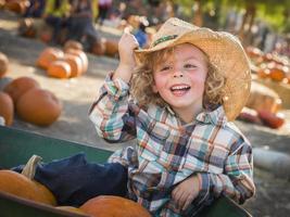 niño pequeño con sombrero de vaquero en el huerto de calabazas foto