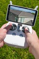manos sosteniendo un controlador de cuadricóptero de drones con una imagen de techo residencial en la pantalla foto