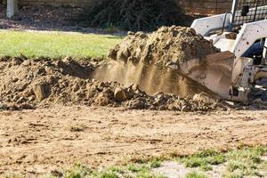 Small Bulldozer Digging In Yard For Pool Installation photo