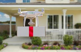 Unmanned Aircraft System UAV Quadcopter Drone Delivering Box With Red Ribbon To Home photo