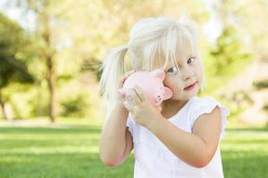 niña divirtiéndose con su alcancía afuera foto