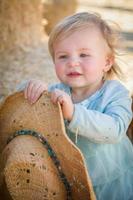 adorable niña con sombrero de vaquero en el huerto de calabazas foto