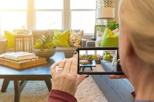 mujer tomando fotos de una sala de estar en una casa modelo con su teléfono inteligente