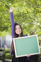 estudiante de raza mixta emocionada sosteniendo pizarra en blanco foto