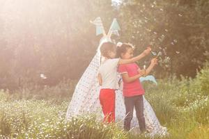 childhood and hygge concept - happy little girls playing in kids tent photo