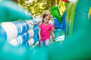 Happy little girl having lots of fun on a jumping castle during sliding. photo