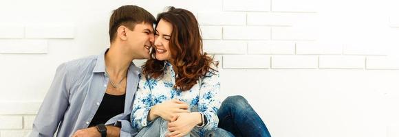 The happy man and woman sit on the background of the white wall photo