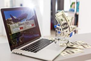 un carrito de compras con dinero con una computadora portátil el concepto de compras en internet.compras en línea foto
