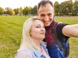 Closeup shot of young couple take selfie outdoor. Young man taking a photo with his girlfriend. Happpy smiling couple taking a selfie in a summer day