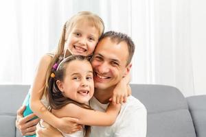 Happy dad carrying two little cute child girl on back giving kid piggyback ride having fun together, smiling single father playing with daughter embracing daddy laughing looking at camera, portrait photo