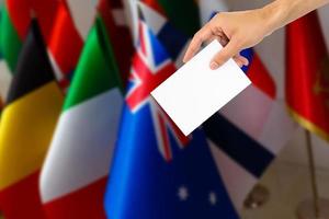 Election or referendum in Great Britain. Voter holds envelope in hand above vote ballot. British and European Union flags in background photo