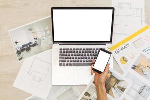 Construction engineer and architect's desk with house projects, laptop, tools and wood swatches top view, male hands drawing photo