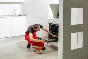 oung man repairing oven in kitchen photo