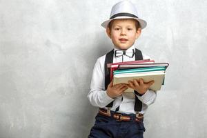 Elementary school student carrying notebooks over a gray background photo