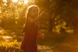 Five years old caucasian child girl blowing soap bubbles outdoor at sunset - happy carefree childhood. photo