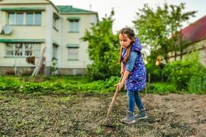 niña en un día soleado en el jardín con una azada foto