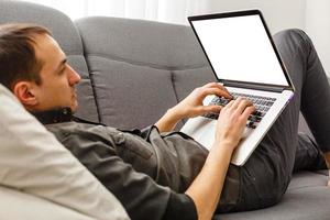 High angle view of young man using his laptop in bright living room photo