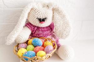 Conejito gracioso entre huevos de Pascua en hierba de terciopelo aislado en blanco foto