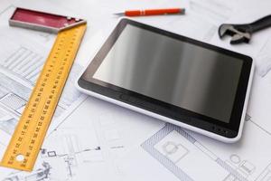High angle view of tablet PC with blueprint and model structure on table photo