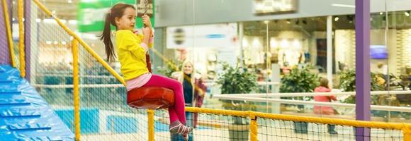 Child jumping on colorful playground trampoline. Kids jump in inflatable bounce castle on kindergarten birthday party Activity and play center for young child. Little girl playing outdoors in summer photo