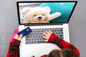 Little girl Hands holding credit card and using laptop.Online shopping in childhood. photo