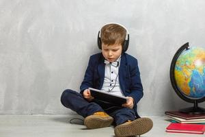 Cute little boy using tablet on grey textured background photo