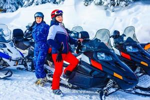 Beautiful girl sitting on a snowmobile at a ski resort photo