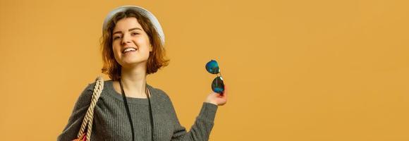 Traveler tourist woman in summer casual clothes, hat with suitcase isolated on yellow orange background. Female passenger traveling abroad to travel on weekends getaway. Air flight journey concept photo