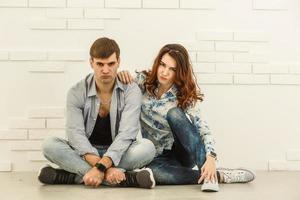 The happy man and woman sit on the background of the white wall photo