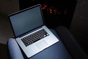 laptop with blank screen for copyspace on wooden table on fireplace background photo