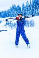 Portrait of pretty skier in blue overalls at a ski resort photo