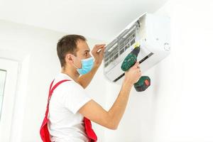 Male technician cleaning air conditioner indoors photo